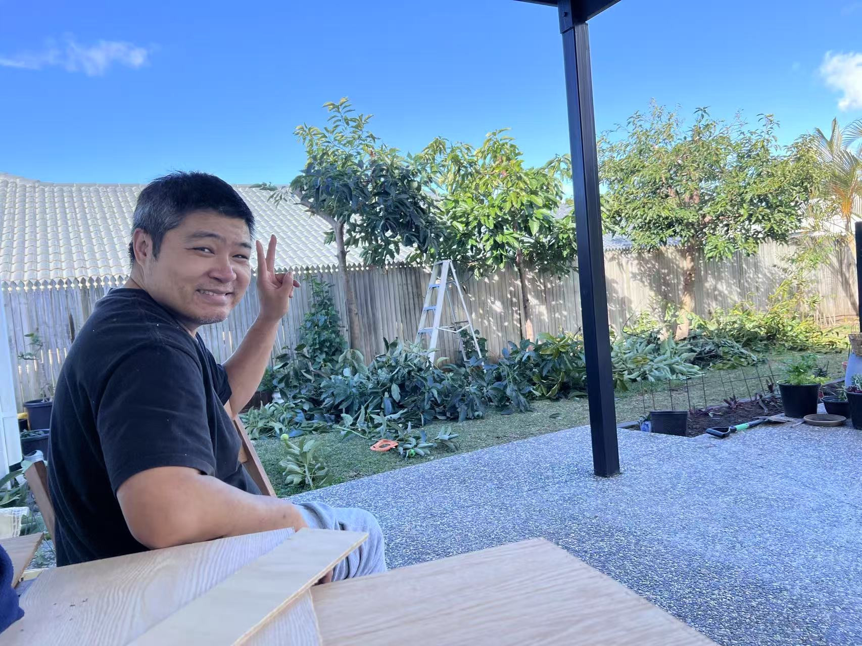 Matthew smiling and waving in a backyard after pruning trees
