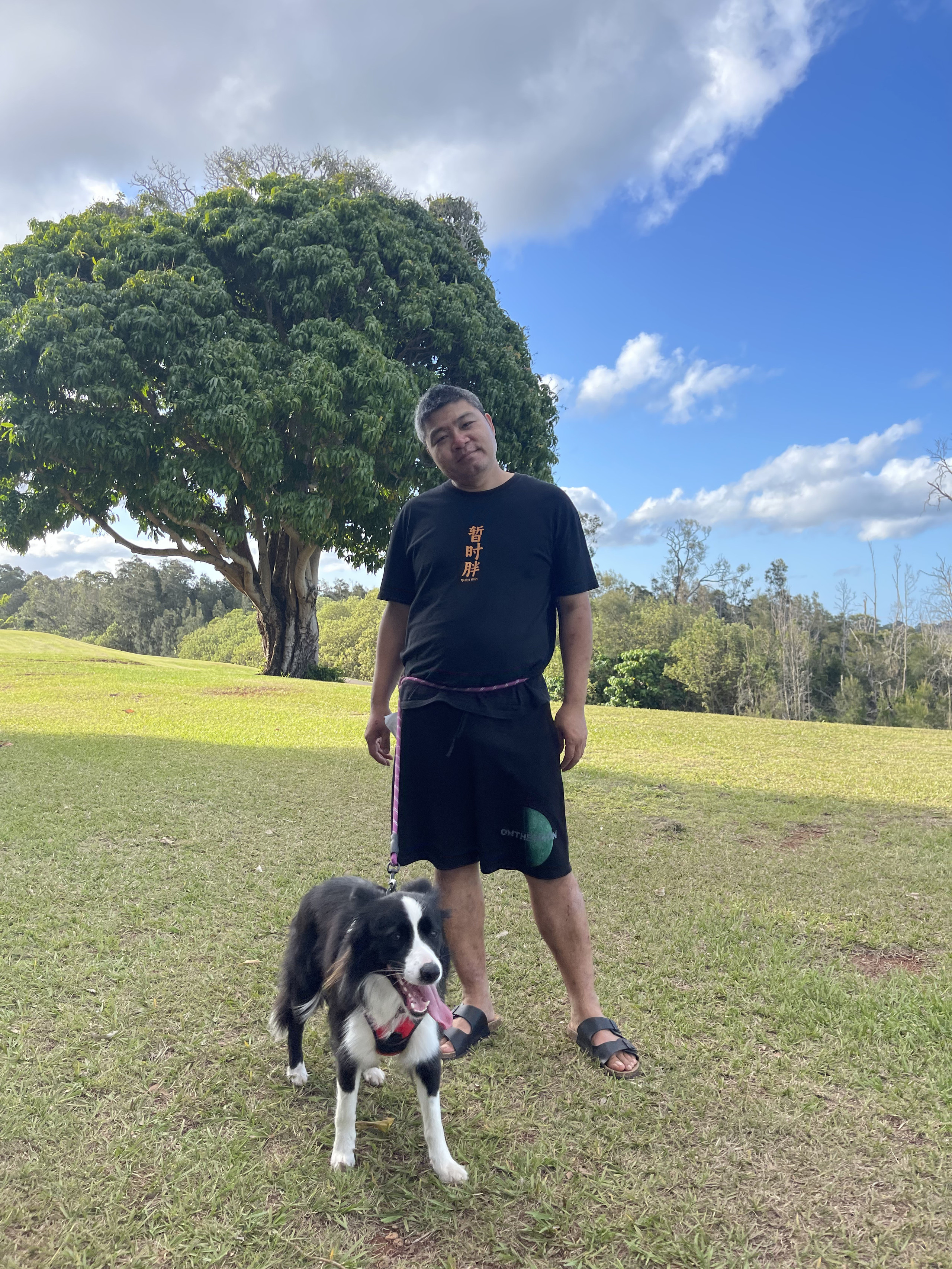 Matthew with a black-and-white sheepdog in a sunny park